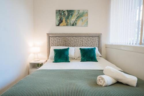 - une chambre avec un lit doté d'oreillers verts et blancs dans l'établissement Spacious Two-Bedroom Apartment - Parking, 7 Mins from Station, Ideal for Business or leisure Stays By AV Hughes Properties, à Milton Keynes