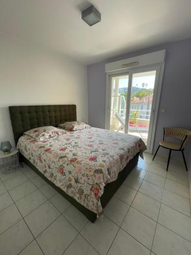 a bedroom with a bed and a chair and a window at Prince de Galles in Cannes