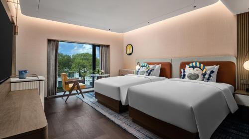 two beds in a hotel room with a large window at voco Xitang by IHG in Jiaxing