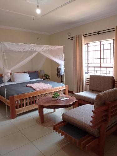 a bedroom with a canopy bed and a chair at 47 The Heights, Area 47, Sector 1, Lilongwe in Lilongwe