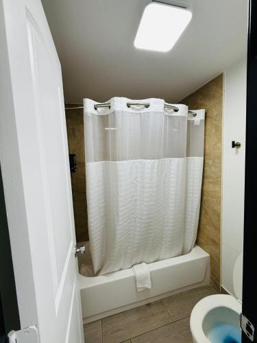 a bathroom with a shower with a white shower curtain at Lone Star Inn Llano in Llano