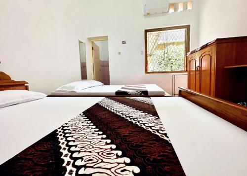 two beds in a bedroom with a rug on the floor at Santalum Hotel Yogyakarta in Yogyakarta