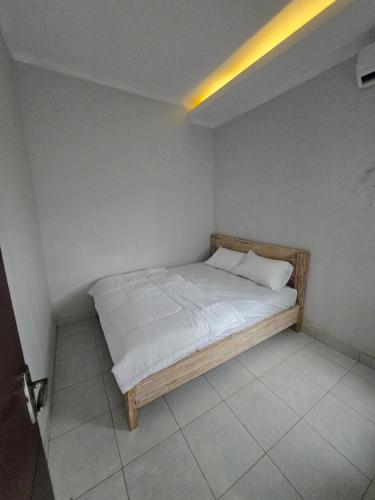 a bed with white sheets and pillows in a room at Gubug Semesta A7 in Krambitan