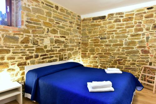 a bedroom with a blue bed in a brick wall at Petra Holiday Home in Pietrapertosa
