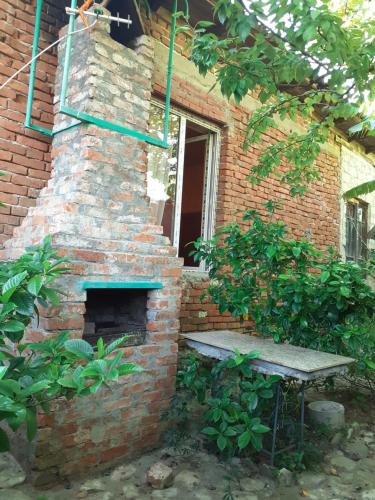 a brick fireplace with a bench in front of a building at Hostel Martvili Tasia in Martvili