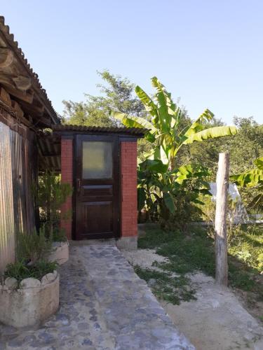a small house with a wooden door next to a garden at Hostel Martvili Tasia in Martvili