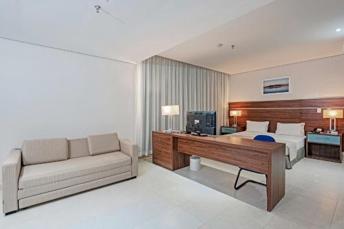 a bedroom with a bed and a desk and a couch at Slaviero Porto Velho in Porto Velho