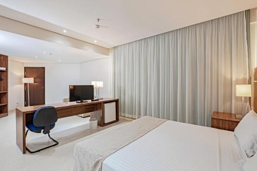 a hotel room with a bed and a desk and a computer at Slaviero Porto Velho in Porto Velho