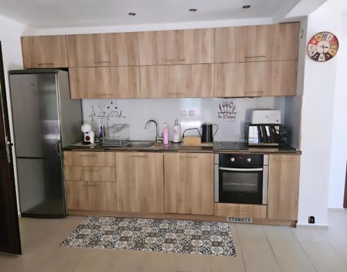 a kitchen with wooden cabinets and a refrigerator at Къща за гости Вила Чифлици in Chiflik