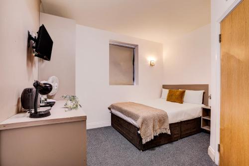 a hotel room with a bed and a television at Belvilla Ilford Hill Hotel London in Ilford