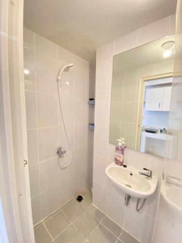 a white bathroom with a sink and a shower at Tokyo River side PIK2 By Micky Studio 5 in Muara