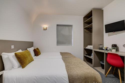 a hotel room with a bed and a desk at Belvilla Ilford Hill Hotel London in Ilford
