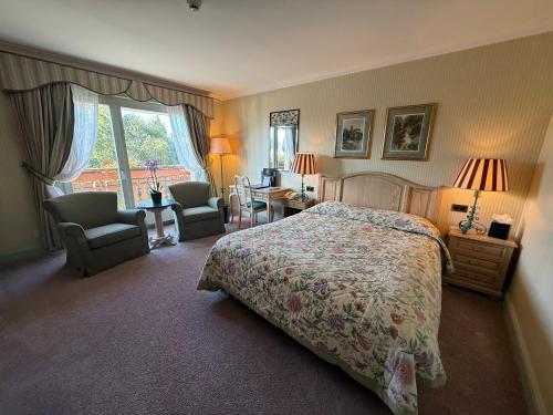 a bedroom with a bed and two chairs and a window at Grand Hôtel du Golf & Palace in Crans-Montana