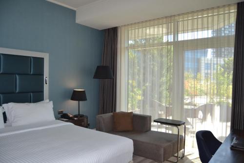 a bedroom with a bed and a chair and a window at Wyndham Grand Istanbul Europe in Istanbul