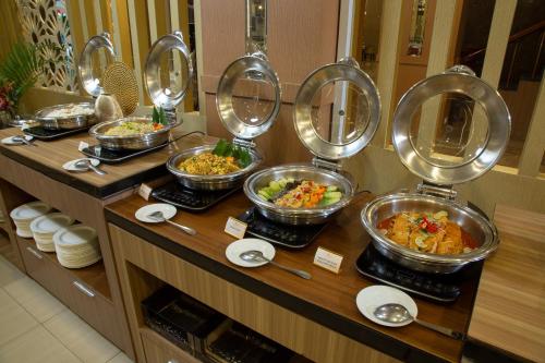 a buffet line with bowls of food in a restaurant at Grand Inna Tunjungan Hotel Surabaya in Surabaya