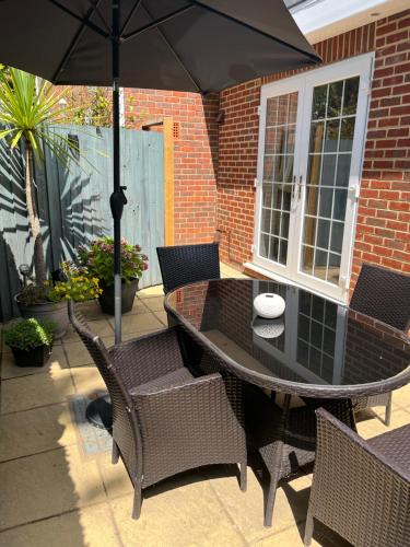 a table and chairs with an umbrella on a patio at Sun Terrace Lodge Weybridge in Oatlands Park