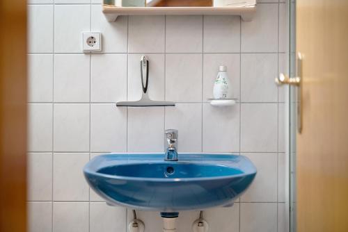 a blue sink in a white tiled bathroom at Gästehaus Weingut Mangel in Endingen