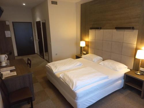a bedroom with a large white bed and a desk at Vlantana in Klaipėda