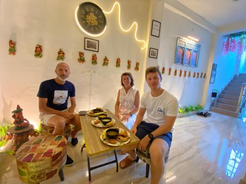 バラナシにあるKasha Homestayのテーブルのある部屋に座っている3人のグループ