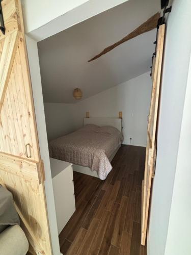 a small bedroom with a bed and a wooden floor at Studio proche de Jonzac in La Celle-sous-Gouzon