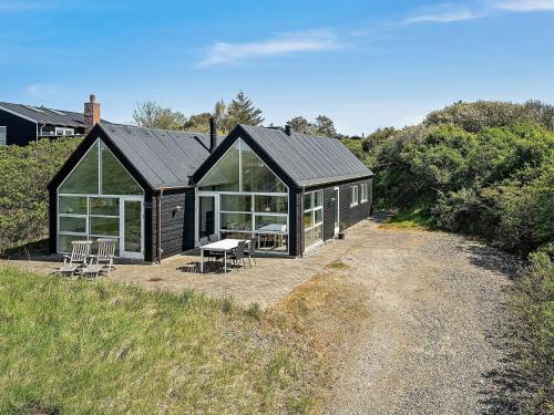ブロックフスにある6 person holiday home in Blokhusの黒いキャビン(野原のテーブルと椅子付)
