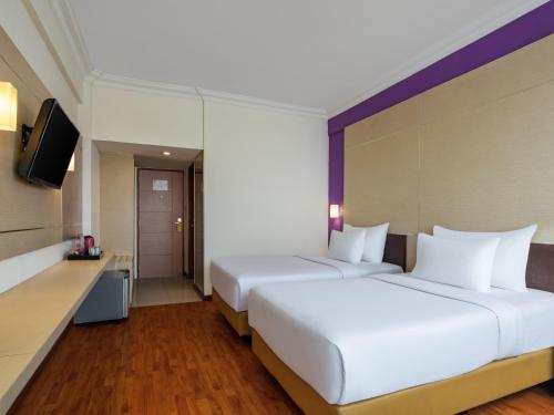 a hotel room with two beds and a television at Grand Inna Tunjungan Hotel Surabaya in Surabaya