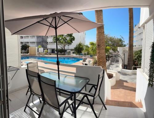 una mesa de cristal y sillas con sombrilla en el patio en Casa Giorì playa de las Americas, en Playa de las Américas