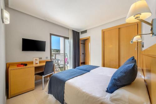 a hotel room with a bed and a desk and a television at Hotel Vibra s'Estanyol in San Antonio Bay