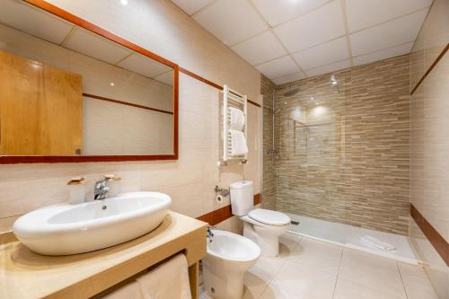 a bathroom with a sink and a toilet and a mirror at Hotel Vibra s'Estanyol in San Antonio Bay