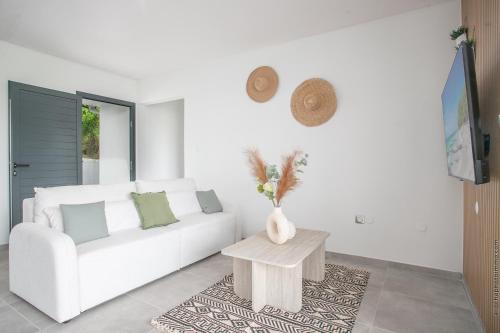 a living room with a white couch and a table at Villa Milo et Malou Classé Meublé tourisme 5 étoiles in Le Marin