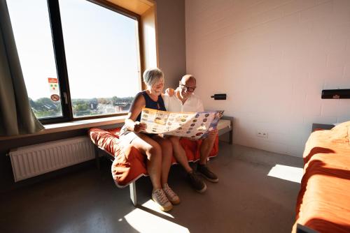 two women sitting on a bench looking at a map at Hostel Groeninghe in Kortrijk
