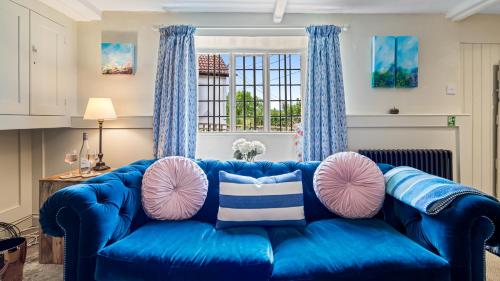 a blue couch with pink and white pillows on it at Myrtle Cottage in Longhope