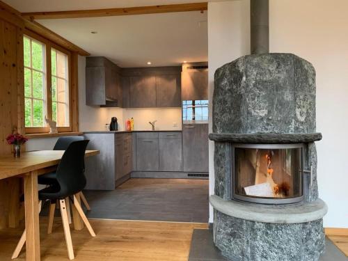 a living room with a stone fireplace in a kitchen at Neuwertiges 2 Zi Ferienchalet 55M2 in Monstein