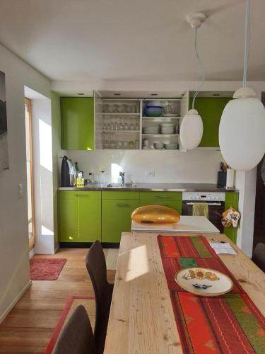 a kitchen with green cabinets and a wooden table at Chesa Vista Mezdi 6 Bergbahnen Sommer Und Öv Inklusive in Pontresina