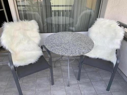 two chairs and a table and a table and chairs with white fur at Ferienwohnung Gian in Davos