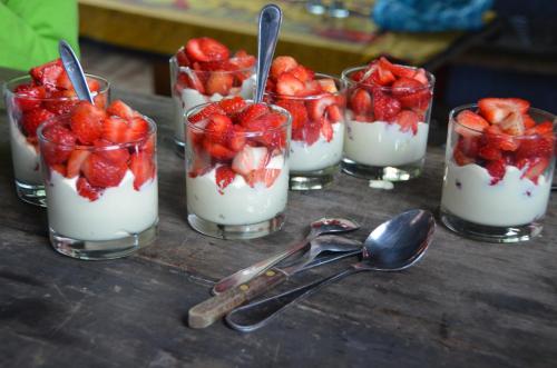 a group of four glasses filled with strawberries and whipped cream at La Brújula Hostel in La Paloma
