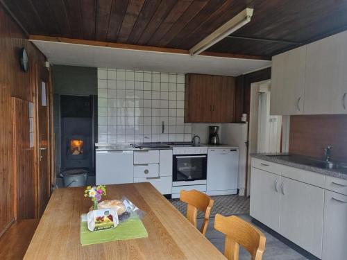 a kitchen with a wooden table and a kitchen with white appliances at Bio Hof Brudersrüti in Schwarzenberg