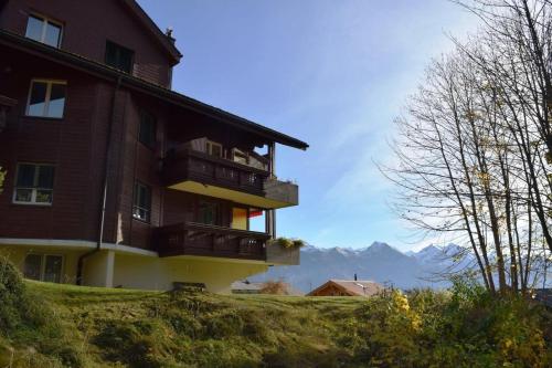 a building on a hill with mountains in the background at Haus Ahorni in Beatenberg