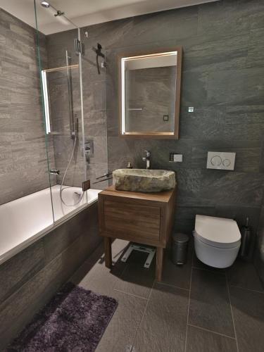 a bathroom with a sink and a tub and a toilet at Exklusive Ferienwohnung Im Hotel Mit Wellness in Laax