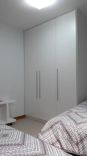 a white bedroom with white cabinets and a bed at Apartamento na Ponta Verde in Maceió