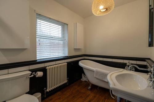 een badkamer met een bad, een wastafel en een raam bij Gorleston Beach House by Leap Escapes in Gorleston-on-Sea