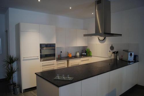 a kitchen with white cabinets and a black counter top at Ferme D Alma in Ocourt