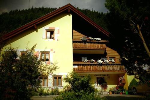 a white house with a balcony with flowers on it at Ers Curtins in Zernez