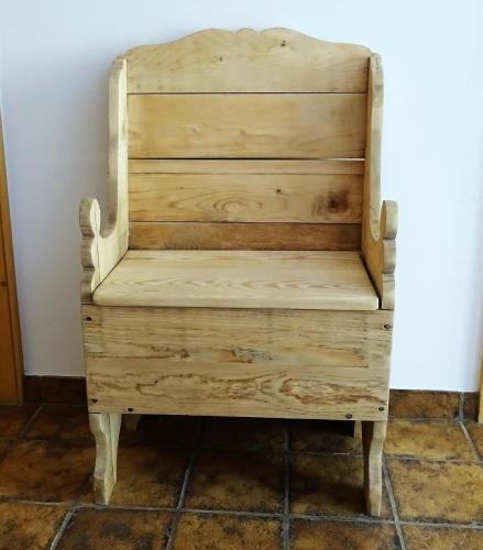a wooden chair in a corner of a room at Ers Curtins in Zernez
