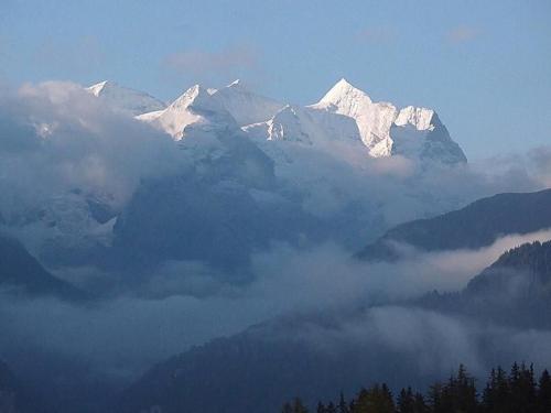 a group of snow capped mountains above a layer of clouds at Chalet Hofer in Hasliberg Wasserwendi
