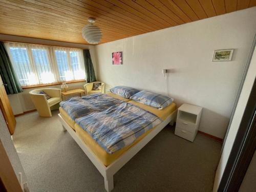 a bedroom with a bed and a chair in a room at Chalet Hofer in Hasliberg Wasserwendi