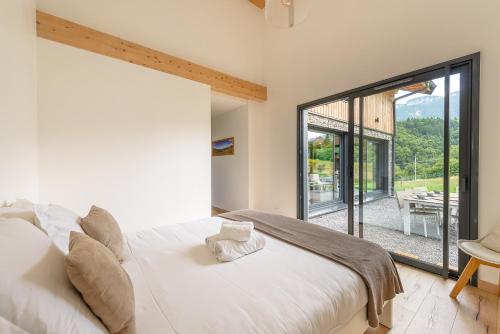 ein Schlafzimmer mit einem weißen Bett und einem großen Fenster in der Unterkunft Villa Alésia - Jacuzzi et vue montagnes, environnement apaisant in Saint-Eustache