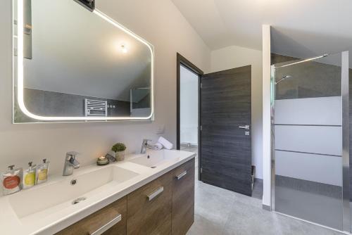 ein Badezimmer mit Waschbecken und großem Spiegel in der Unterkunft Villa Alésia - Jacuzzi et vue montagnes, environnement apaisant in Saint-Eustache