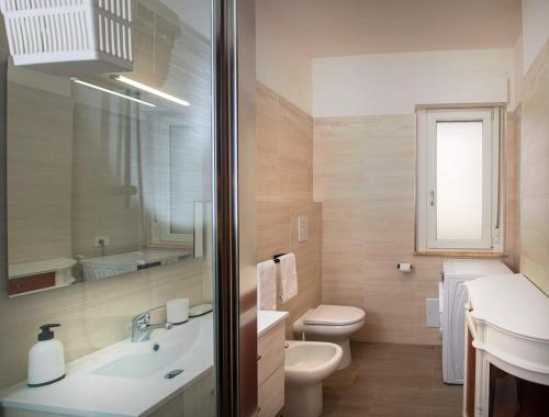 Un baño con lavabo, inodoro y espejo. en Monsoni House, en Cagliari