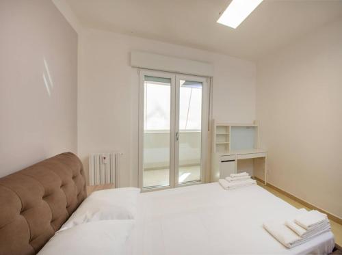 Un dormitorio blanco con una cama grande y una ventana. en Monsoni House, en Cagliari